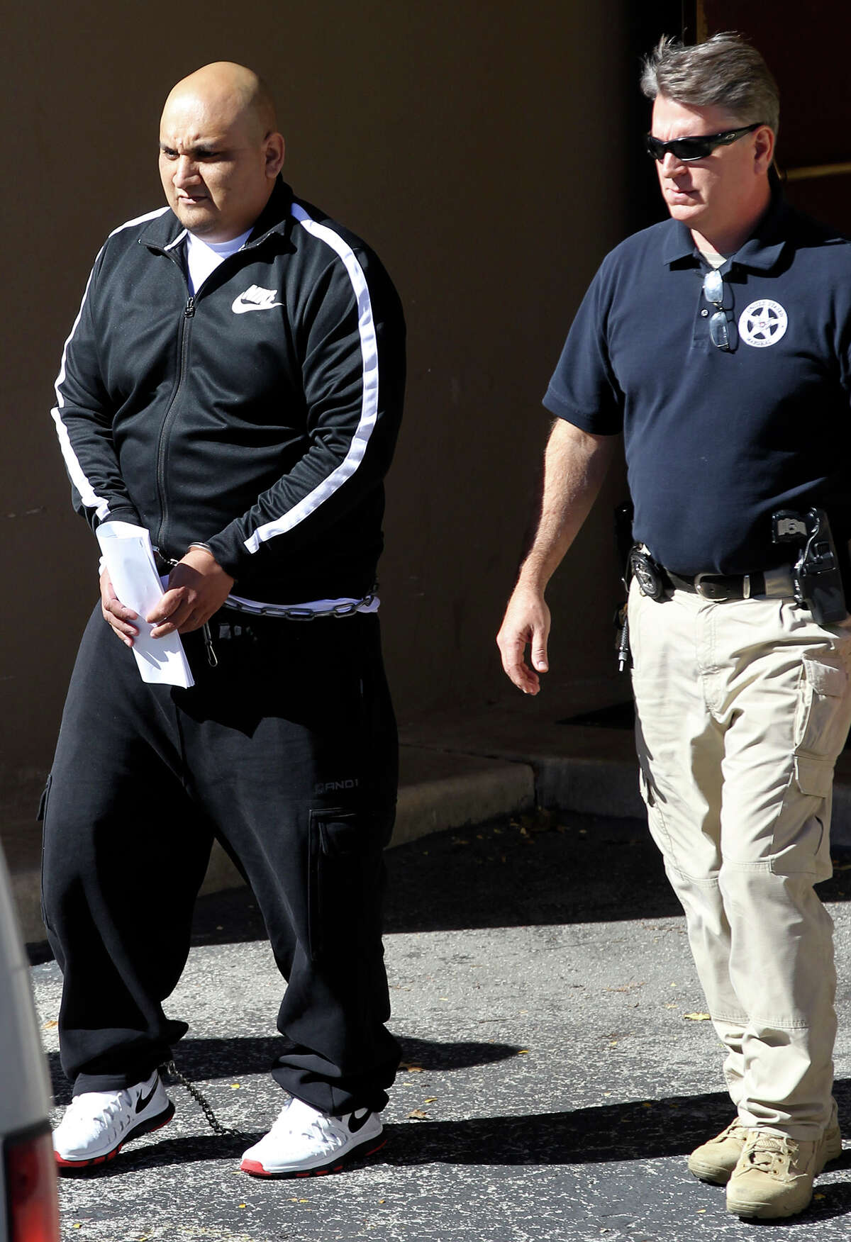 Ruben Reyes (left) is escorted Wednesday November 26, 2014 out of the Federal Courthouse in San Antonio, Texas. Reyes,36, is a purported enforcer for the Texas Mexican Mafia and was arrested on charges he killed three high-ranking members of the same gang and is also suspected of having given orders to kill Balcones Heights Police Officer Julian Pesina.