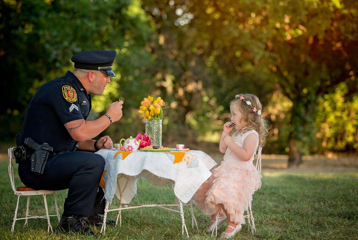 Cpl. Patrick Ray of the Rowlett Police Department has tea with Bexley Norvell, 2, on July 17, 2016, in Rowlett. Photographer Chelle Cates said the tea party photo shoot celebrated the first anniversary of Ray saving Bexley from choking on a small coin.