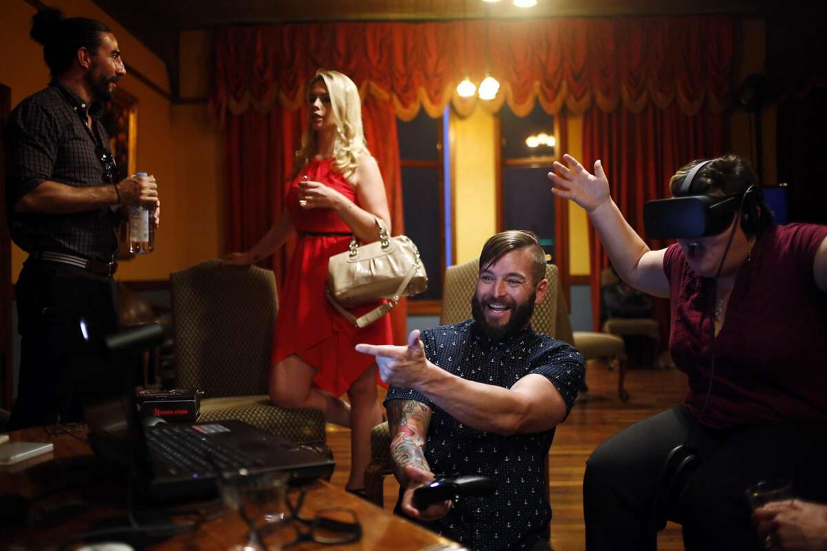 Jimmy Hess (center) of Vixen VR shows off the program as Vixen's Dan Dilallo (left) discusses the business during a gathering of virtual reality pornography enthusiasts and businesses at Kink.com headquarters in San Francisco, California, on Thursday, July 28, 2016.