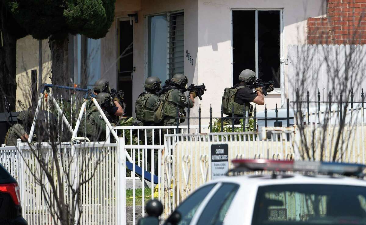 San Diego Police heavily armed police officers surround a house about a half-mile away, urging a man inside to surrender in San Diego Friday, July 29, 2016. One San Diego police officer was killed and another was wounded in a shootout following a late-night traffic stop, Friday night. A suspect was wounded and taken into custody a short time later and hours later police surrounded the home as they searched for man described as a possible accomplice. (AP Photo/Denis Poroy)
