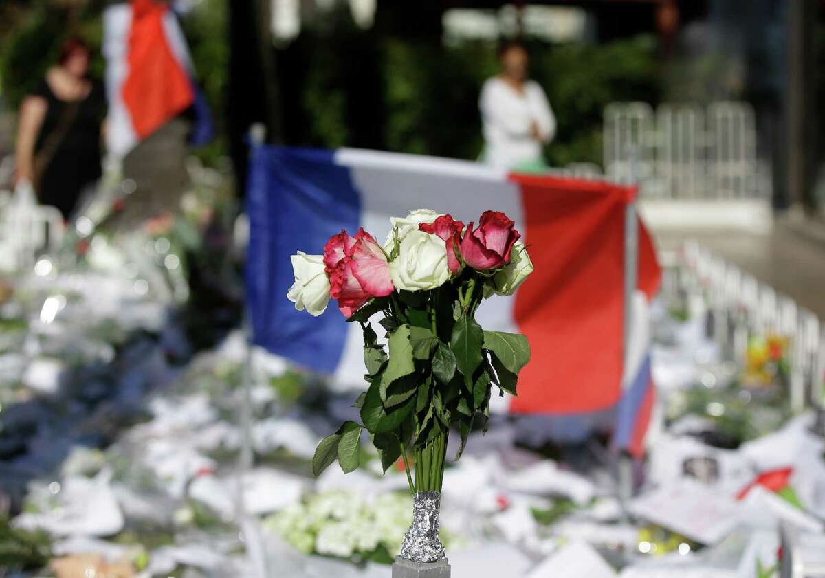 Floral and papers tributes are laid with a French flag near the scene of a truck attack in Nice, southern France, Saturday, July 16. (AP Photo/Luca Bruno)