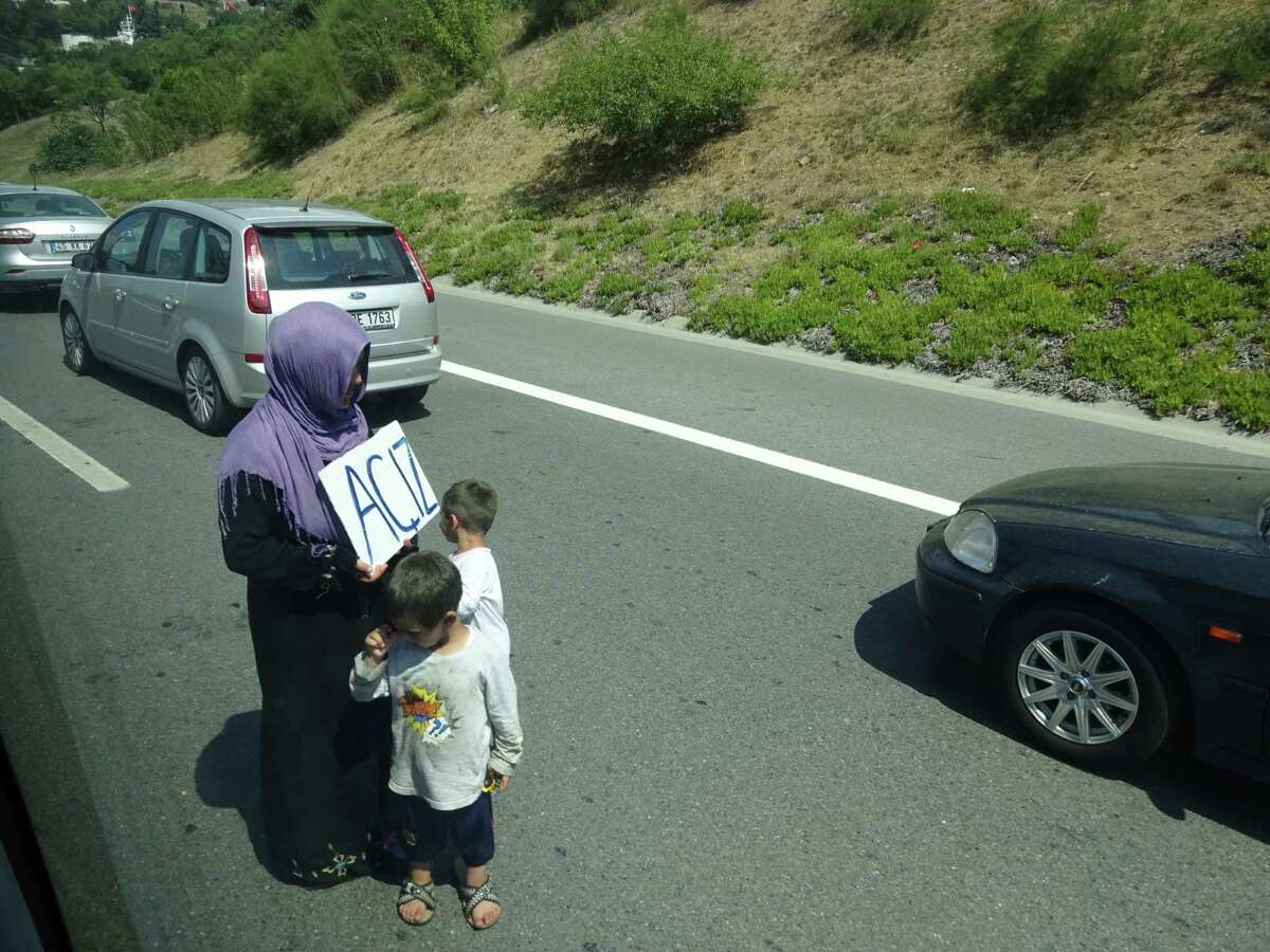 A Syrian refugee woman and her two young children beg for money on a highway in Istanbul during an afternoon traffic jam in the sprawling city of 16 million (Paul Grondahl / Times Union)