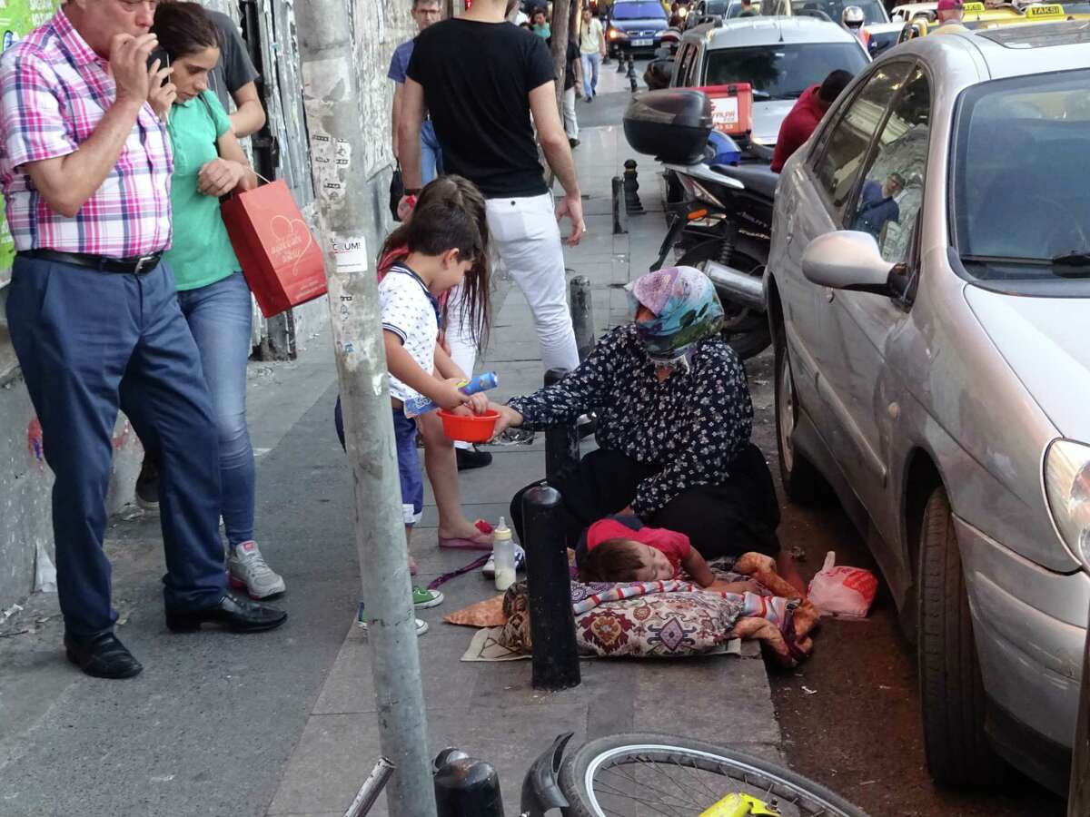 A Syrian refugee woman and her children beg from passersby near Taksim Square in Istanbul (Paul Grondahl / Times Union)