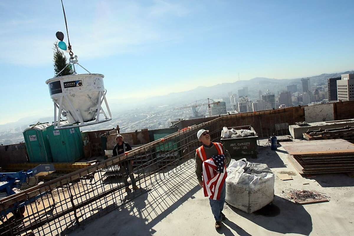 Tommy Miller and Brian Morton (right) help land a concrete bucket with a ceremonial tree inside on the top of Millennium Tower during a ceremonial "topping-off" event in 2008.