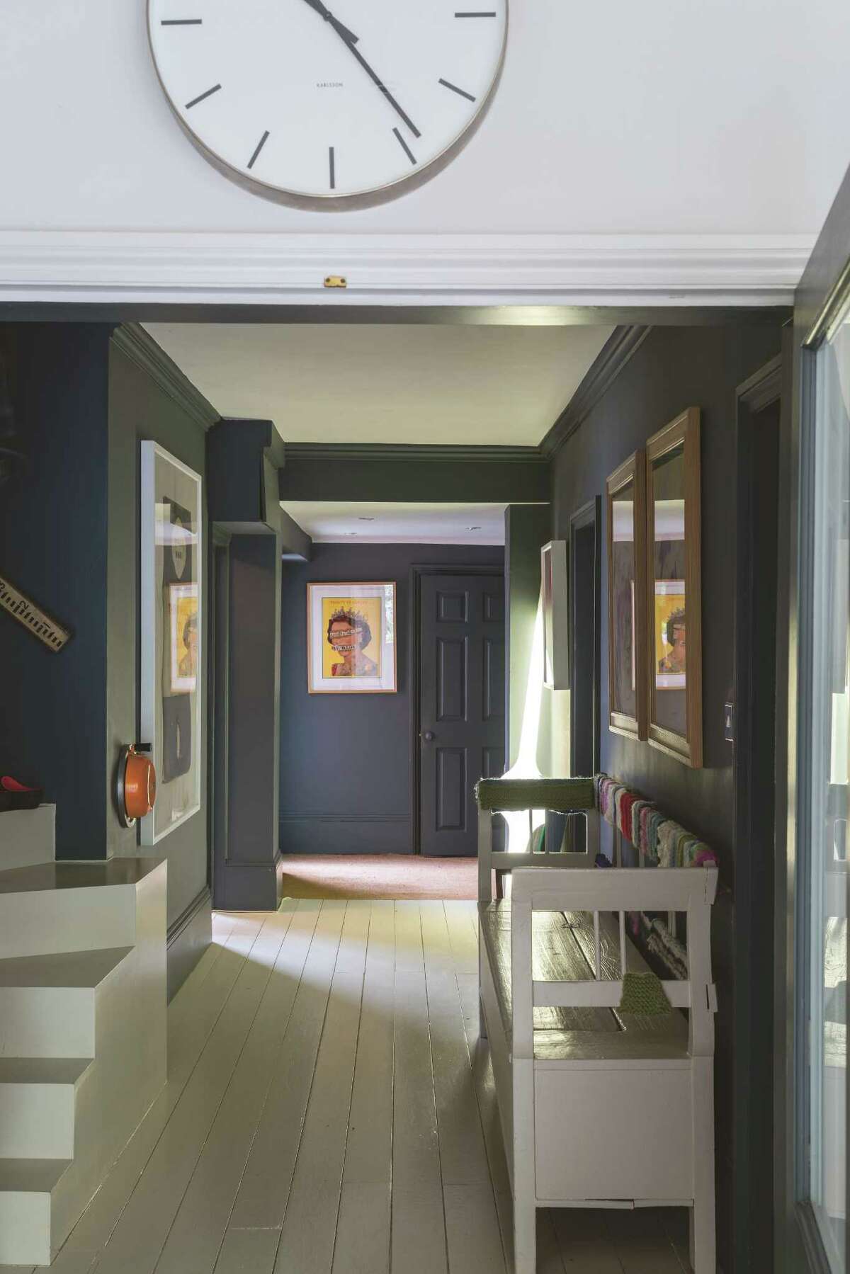The hallway in Joa Studholme's home has dark gray walls﻿. Its white floors reflect light onto the walls to brighten what otherwise could be a too-dark space.﻿