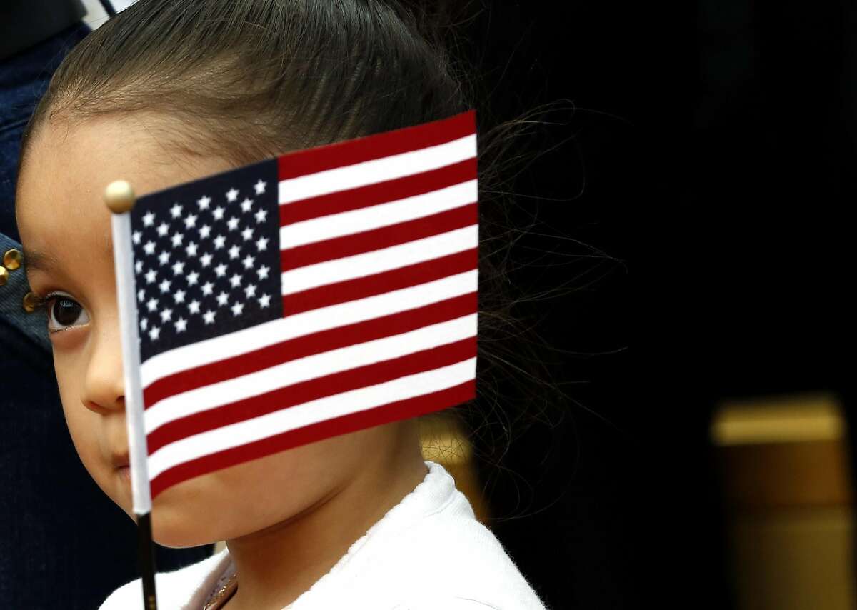 Alma Cecilia Rubalcaba, 4, waves an American flag in front of her face during a naturalization ceremony at Children's Fairyland in Oakland, California, on Monday, August 1, 2016.