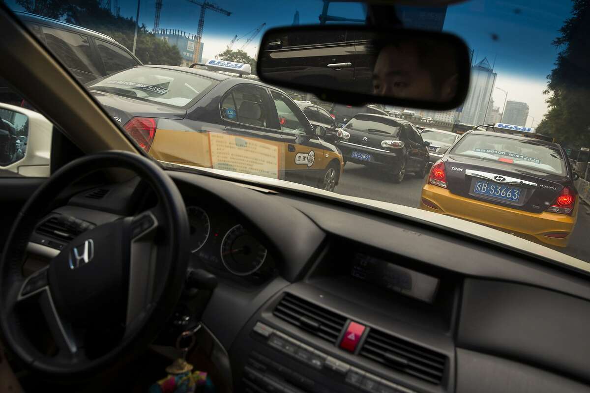FILE-- An Uber driver drives behind taxis in Beijing, May 28, 2015. In a stark signal of how difficult it is for American technology companies to thrive in China, Uber China said on Aug. 1, 2016, it was selling itself to Didi Chuxing, its fiercest rival there. The sale, which would create a new company worth about $35 billion, would end the great ride-hailing battle of China. (Adam Dean/The New York Times)
