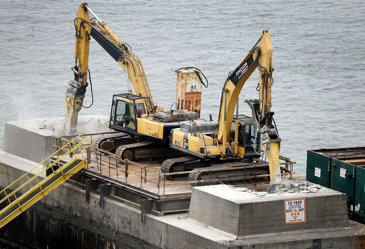 Heavy equipment hammers against the concrete foundation of a pier from the old eastern Bay Bridge as demolition work continues in Oakland, Calif. on Tuesday, Aug. 2, 2016.