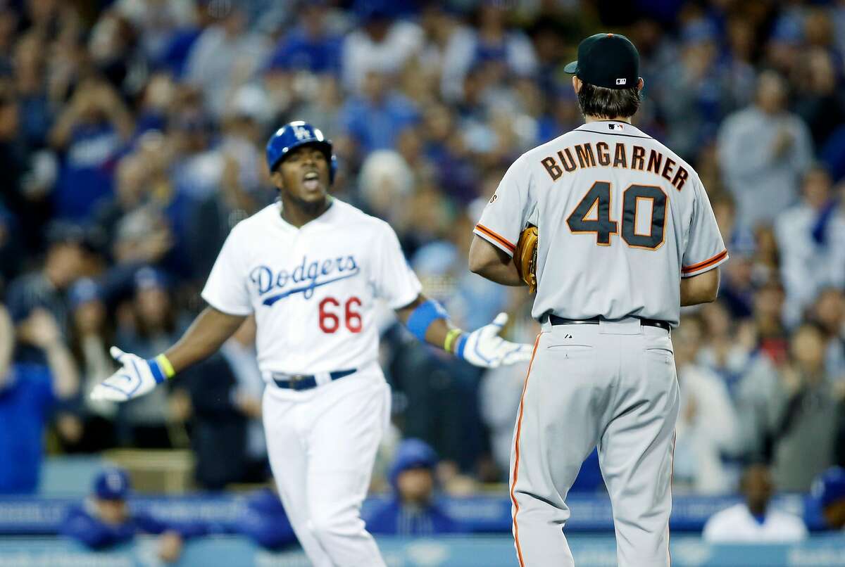San Francisco Giants starting pitcher Madison Bumgarner, right, and Los Angeles Dodgers' Yasiel Puig, left, exchange words as Puig runs down the third base line after hitting a solo home run during the sixth inning of a baseball game, Friday, May 9, 2014, in Los Angeles. (AP Photo/Danny Moloshok)