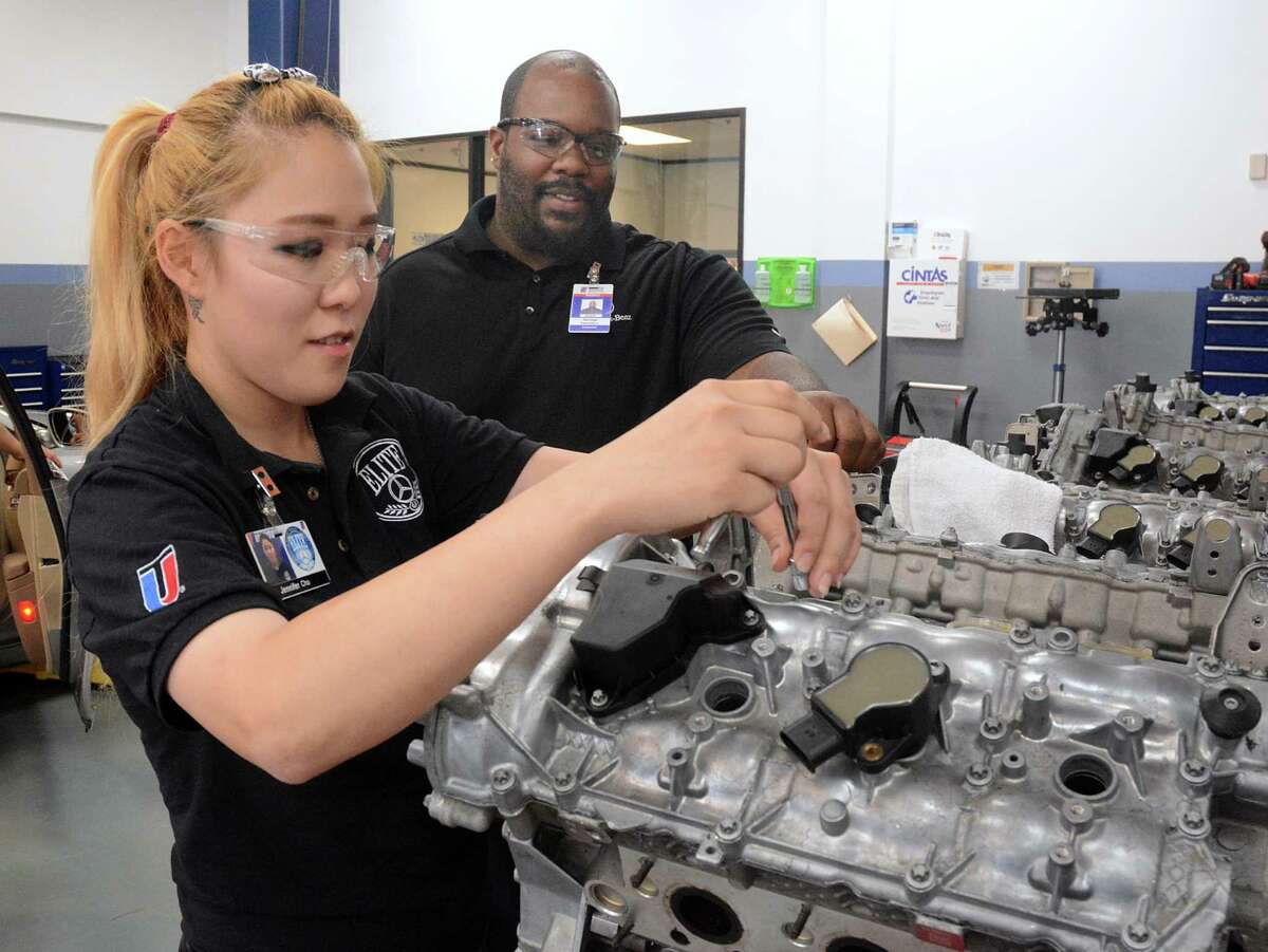 Jennifer Cho trains on an engine block at the Universal Technical Institute as instructor George Hamilton supervises her during a Mercedes Benz car repair class.