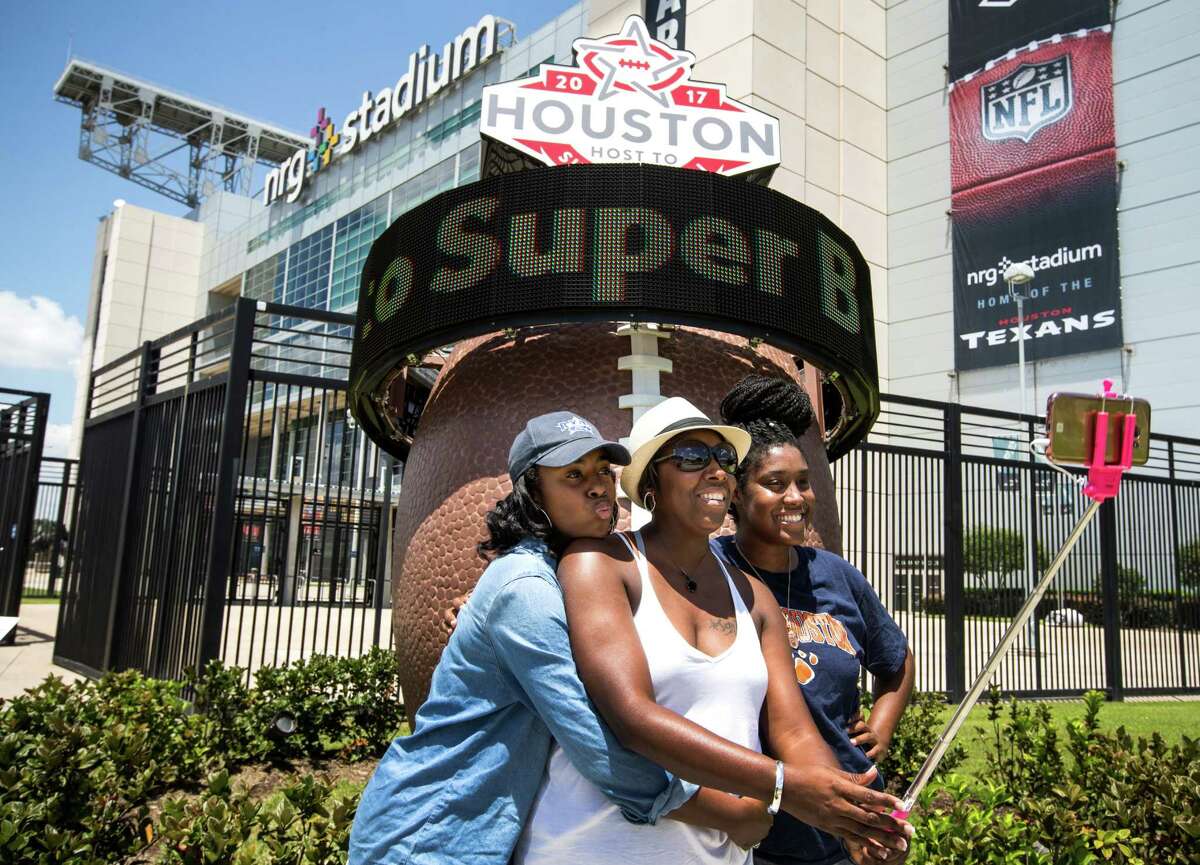 From left, Brittney Lee, Tamika Givens and Destiny Lee pose for a selfie next to the Super Bowl LI countdown clock outside NRG Stadium. The game will be Feb. 5. ﻿