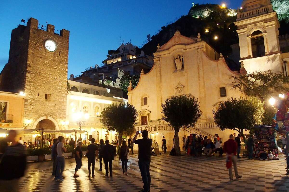Locals and travelers fill Piazza IX Aprile, in front of the San Giuseppe church, in the coastal resort town of Taormina, Sicily.