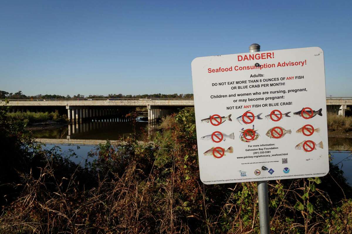 A sign warns fisherman and visitors not to eat contaminated seafood caught from the water along I-10 near the San Jacinto River east of Houston, Tuesday, Dec. 17, 2013, in Channelview ( Michael Paulsen / Houston Chronicle )