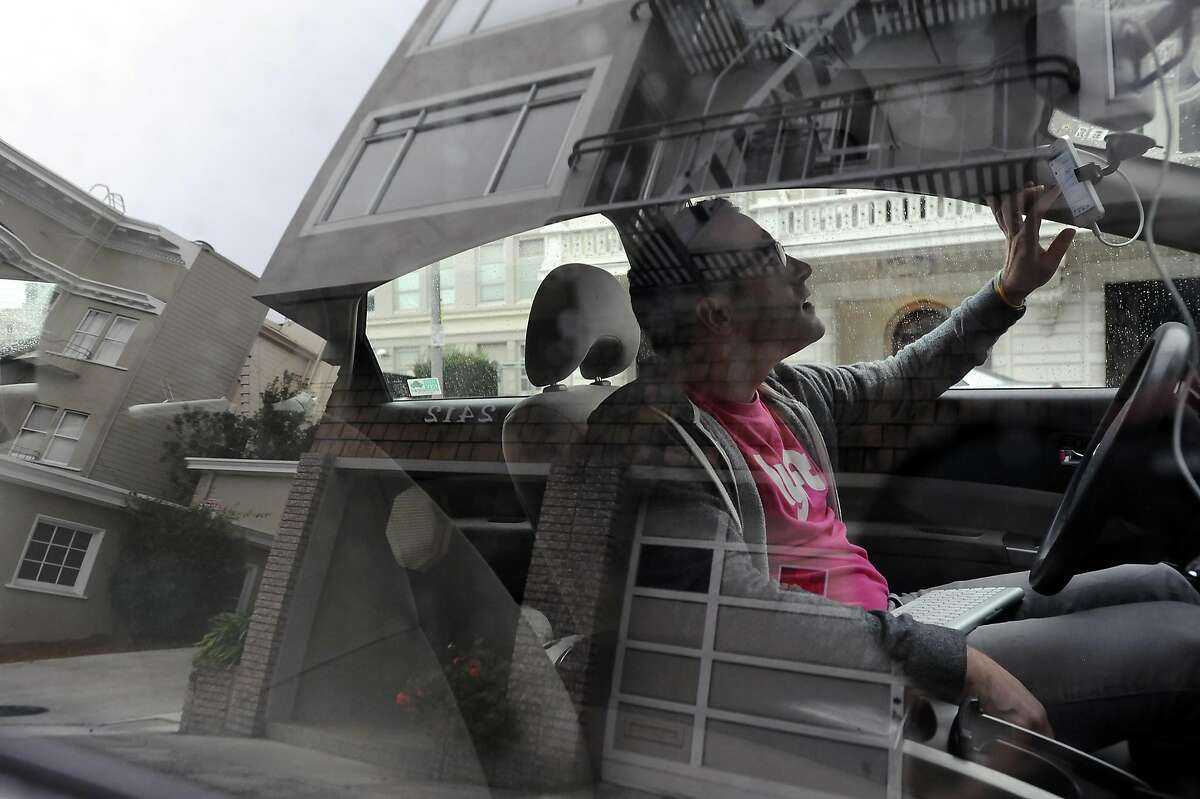 Lyft driver Andrew Kucharski, who is deaf, checks his phone while waiting for customers during a shift in San Francisco, CA, on Wednesday, December 17, 2014. To communicate Andrew uses a keyboard that both he and his passengers can type on which is also synced with his iPhone where the messages are displayed.