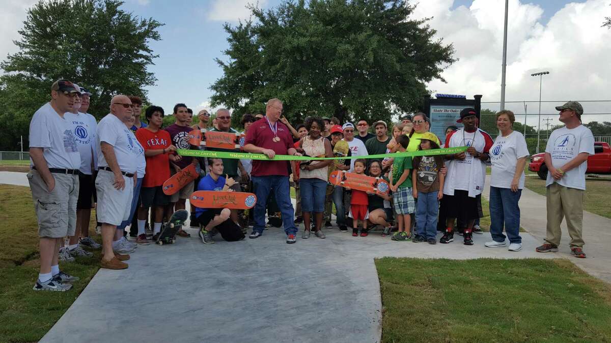 Live Oak Mayor Mary Dennis (center, with scissors) prepares to cut a ribbon Saturday that officially opened the Skate The Oaks Plaza skate park in Live Oak's city park.