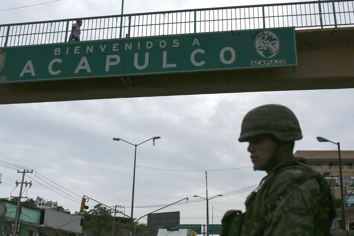 A Mexican soldier stands guard under a footbridge with an inscription that reads Welcome to Acapulco in Acapulco, Mexico on July 14, 2016. With a population of 810,000 the touristic resort of Acapulco ranks as one of the most violent cities in the world, with a crime rate of 111 murders per 100,000 inhabitants in 2015.
