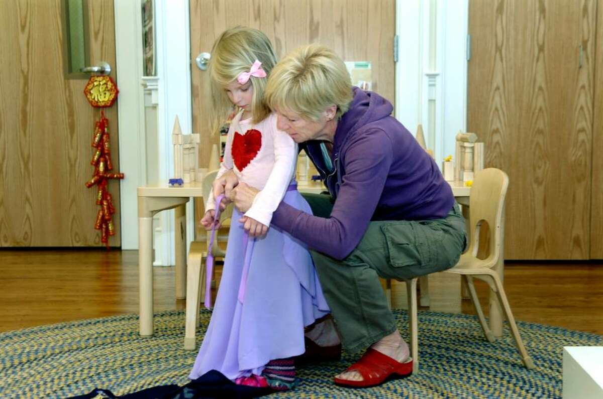 Molly Gleason, right, a teacher at Bridges School, helps Emily Shull, 4, with her dress-up skirt, at the nursery school that has opened on the site of a long-closed teen and community center, on Valley Road, in Cos Cob, on Thursday, Apri 29, 2010.