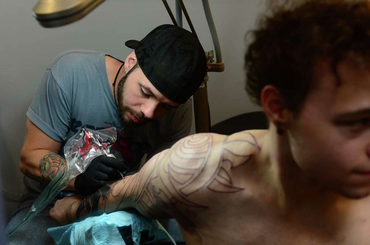 Pieter Spijkers, an artist at Bad Ffish Tattoo, inks a tribal tattoo for client Eric Monaco at the shop in Liberty Plaza in Norwalk.