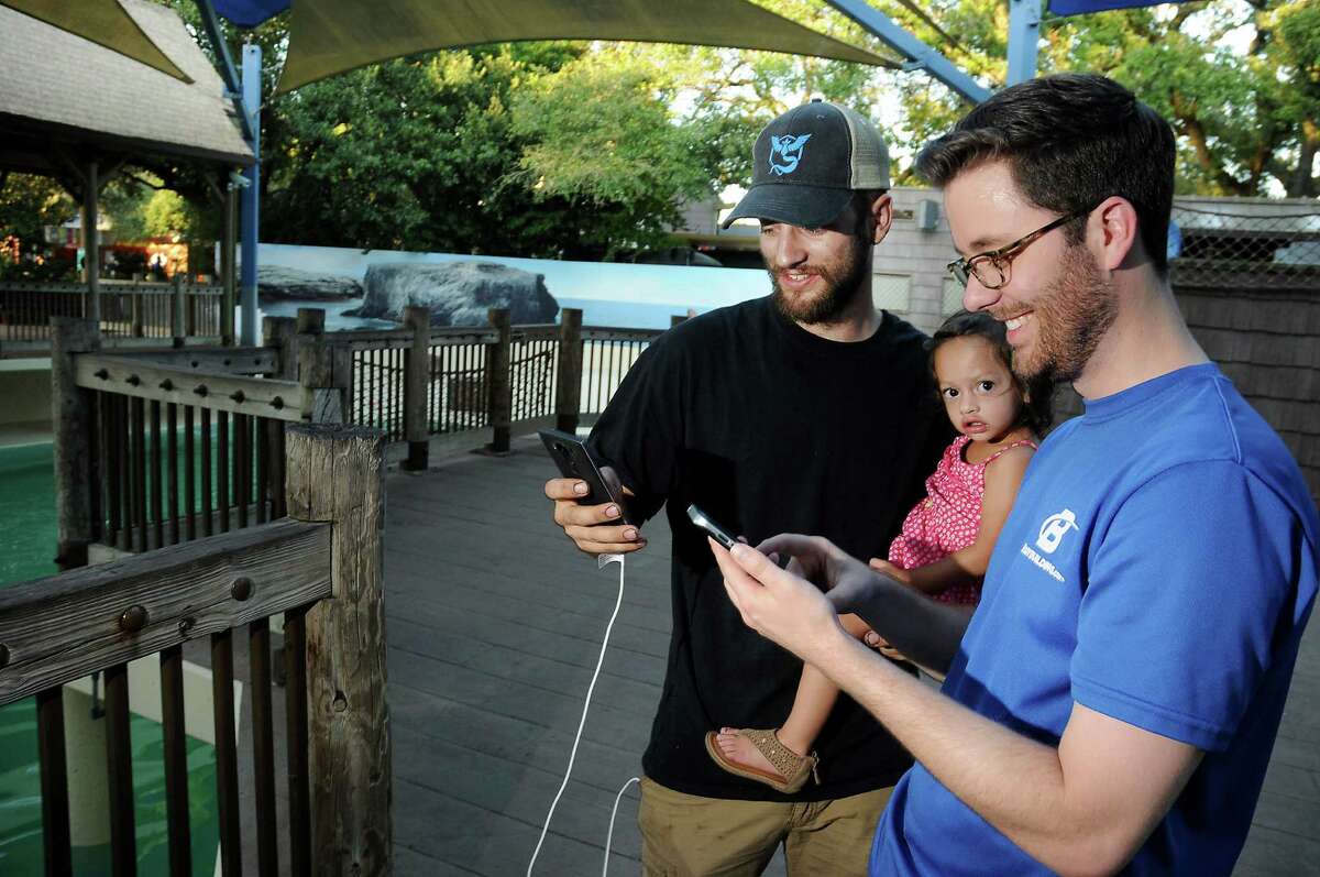 Landon Urban, holding Phoebe, and his brother Chris Urban play Pokemon Go near the sea lions at the Houston Zoo Friday Aug. 05,2016.(Dave Rossman Photo)