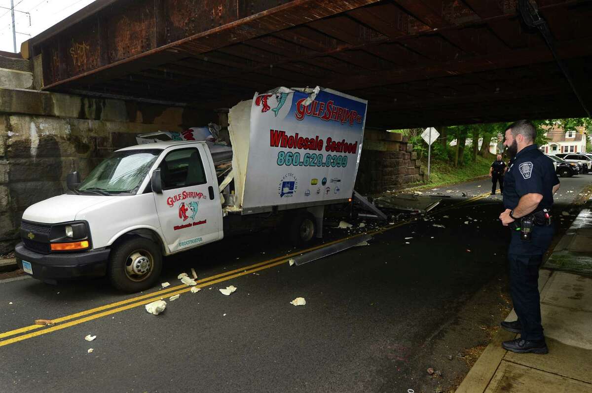 Norwalk police respond to an accident scene where a Gulf Shrimp Co. box truck crashed into the Metro-North Railroad bridge spanning Starwberry Hill Ave in Norwalk, Conn. May 24, 2016. The back of the vehicle was totally destroyed when it hit the bridge with a clearance of 9'6" and left debris strewn acoss the road. The driver was uninjured.