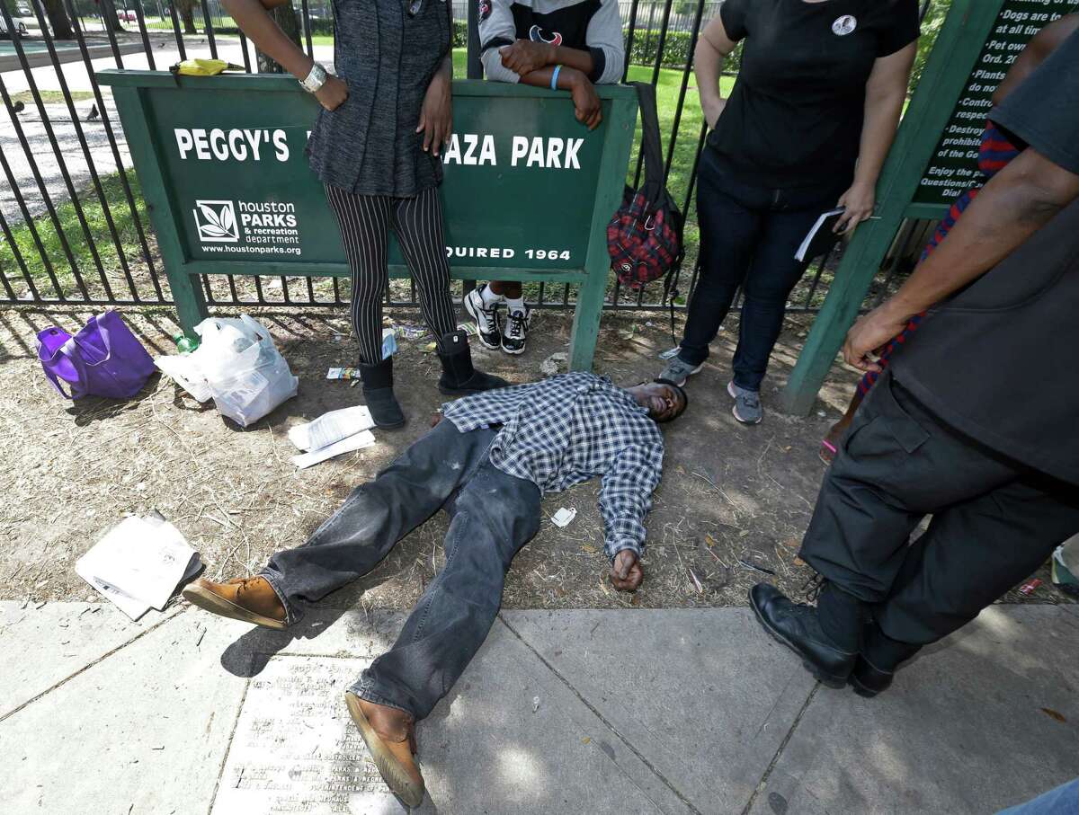 Bystanders watch man who fell down after smoking some Kush in Peggy Park Wednesday, June 29, 2016, in Houston. ( Melissa Phillip / Houston Chronicle )