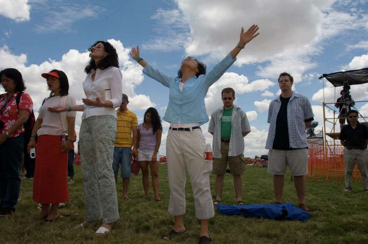 (NYT31) MIDLAND, Texas -- Aug. 8, 2005 -- CHRISTIANS-BUSH -- Myong Sun Hubbard, center, of Bartlesville, Okla., prays with Rev. Phillip Koo of the Midland Korean Church who took the stage with Korean activists at a Christian rock concert near Midland, Texas, Saturday, August 6, 2005. At left Noriko Fix, of Midland, Xianzhi "Sarah" Liu and Traci McConnell, of Bartlesville, Okla., listen and pray. A group of mostly evangelical Christians in President BushÂ?’s hometown held a mammoth Christian rock concert and political rally this weekend to press the president to take a hard line on human rights and religious freedom in North Korea. Their get-tough approach annoys the South Koreans and other Asian allies, but the Christian right is trying to build on its success in pushing the White House to intervene diplomatically in Sudan. (Kevin Moloney/The New York Times) *LITE