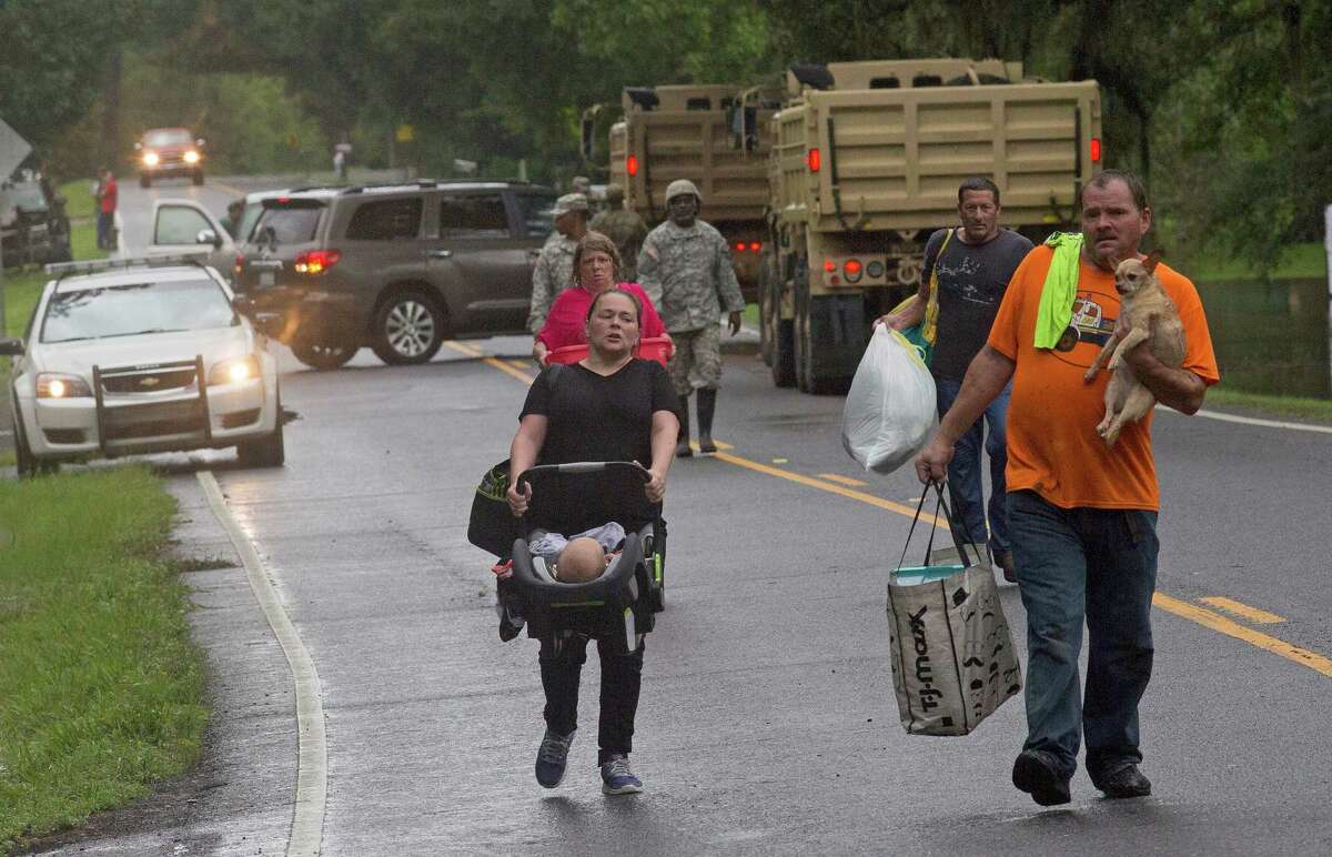 People arrive to be evacuated by members of the Louisiana Army National Guard near Walker, La., after heavy rains inundating the region, Sunday, Aug. 14, 2016. (AP Photo/Max Becherer)