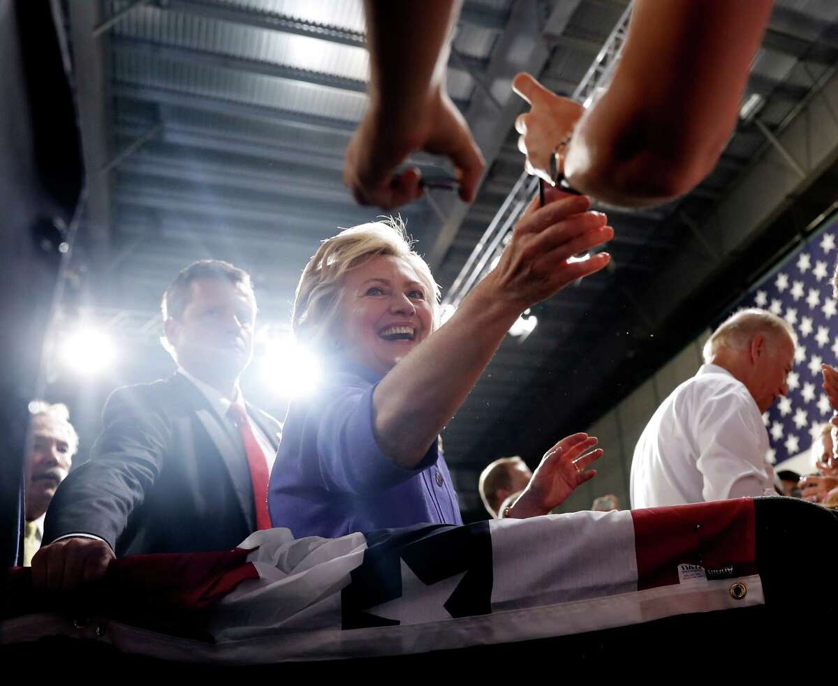 Democratic presidential candidate Hillary Clinton reaches for a cell phone as she and Vice President Joe Biden, right, greet people in the audience after speaking at a campaign event at Riverfront Sports in Scranton, Pa., Monday, Aug. 15, 2016. (AP Photo/Carolyn Kaster)