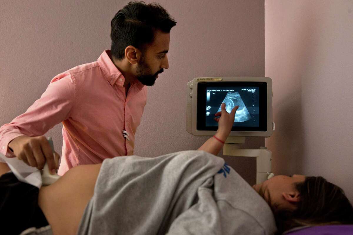 SOCIAL VALUES: Dr. Bhavik Kumar, 31, listens to a question from a patient seeking an abortion during her ultrasound at the Whole Woman's Health clinic in Fort Worth, Texas, on Friday, June 3, 2016. Women considering abortion are required by the state to have a sonogram that they must be offered the chance to view, although they can refuse to look. There is then a required 24-hour waiting period after the initial consultation. Some must travel long distances twice in order to complete the procedure. This patient, who was 6-weeks pregnant and has a previous child, took the sonogram photograph home with her and scheduled the abortion procedure for the next day. In order to serve the women who depend on a dwindling number of abortion providers in Texas, Kumar commutes across the state to clinics in San Antonio and Fort Worth. "We know the need is there," says Kumar. "I feel morally and ethically obligated to do this work." (AP Photo/Jacquelyn Martin)