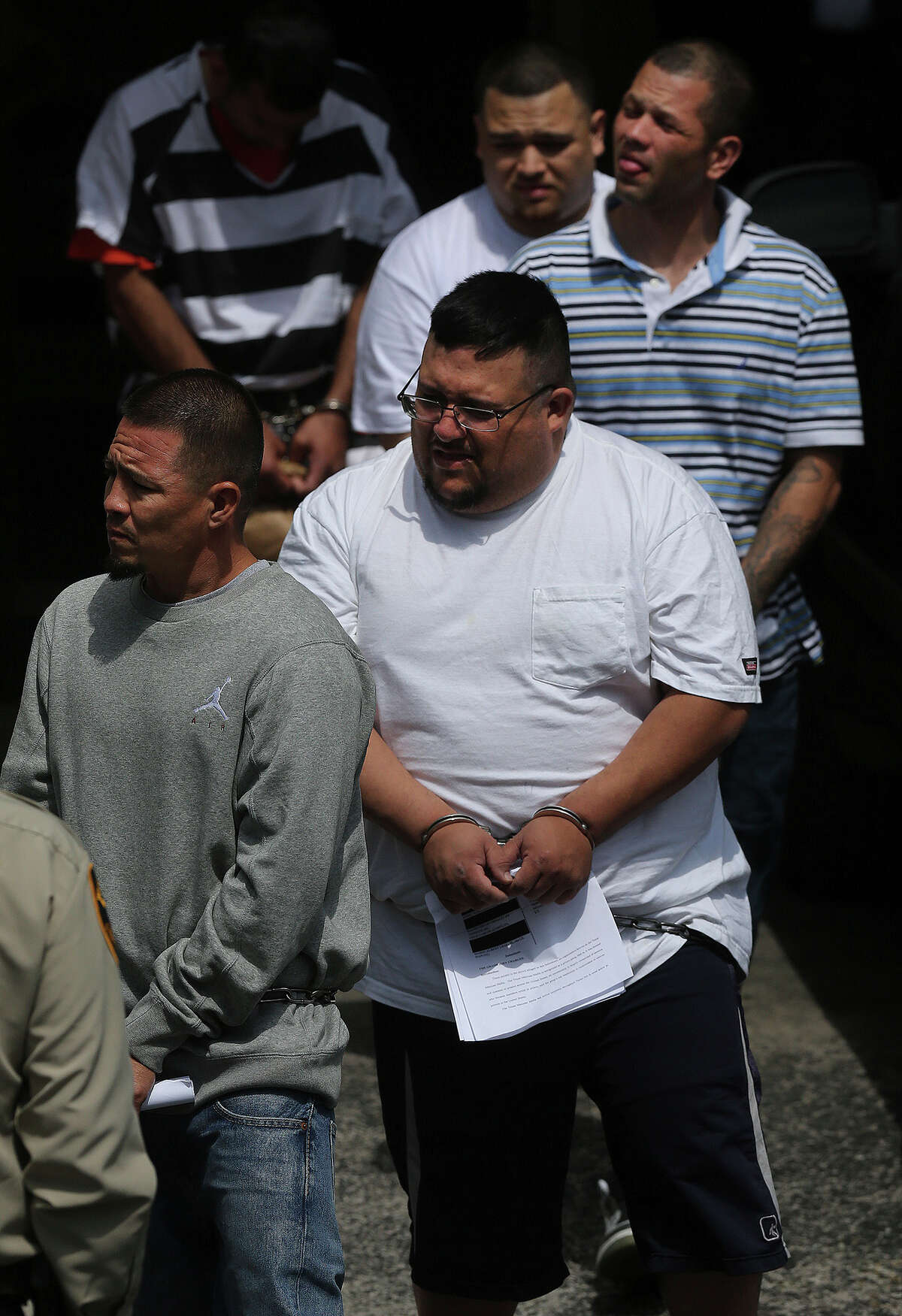 Suspects are led Friday April 15, 2016 out of the John H. Wood, Jr. Federal Courthouse after an area roundup of arrests were made targeting the Mexican Mafia. In front is Mario Albert Leal, Jr., behind him (white shirt, heavy set) is Cruz Carlos Acosta, behind him (striped polo) is David Phillip Urdiales, aka the "termite", and behind him is Eddie Flores.