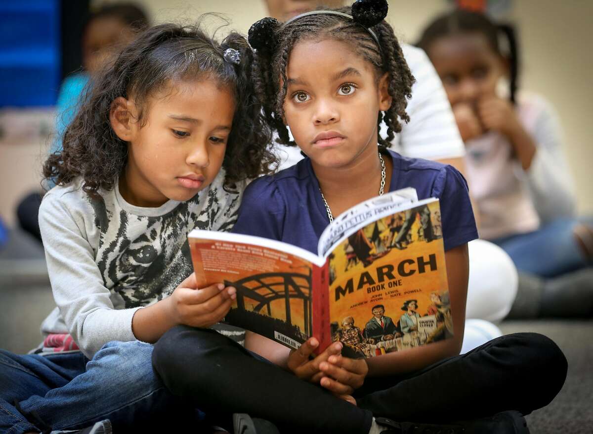 Students Isabella, 6, (left) and Talaya, 6, follow along during a reading of the graphic novel "March" by Representative John Lewis at the Ella Hill Hutch Community Center in the Western Addition neighbor on Tuesday, Aug. 16, 2016.