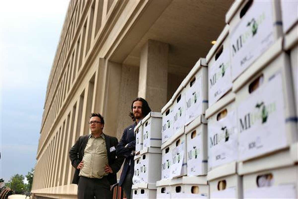 Board members for MILegalize, Josh Covert, of East Lansing, left, and Jeffrey Hank, of East Lansing, right, wait outside the Secretary of State Elections Division with 61 boxes full of around 350,000 petition signatures in Lansing, Mich., Wednesday, June 1, 2016. (Samantha Madar/Jackson Citizen Patriot via AP)