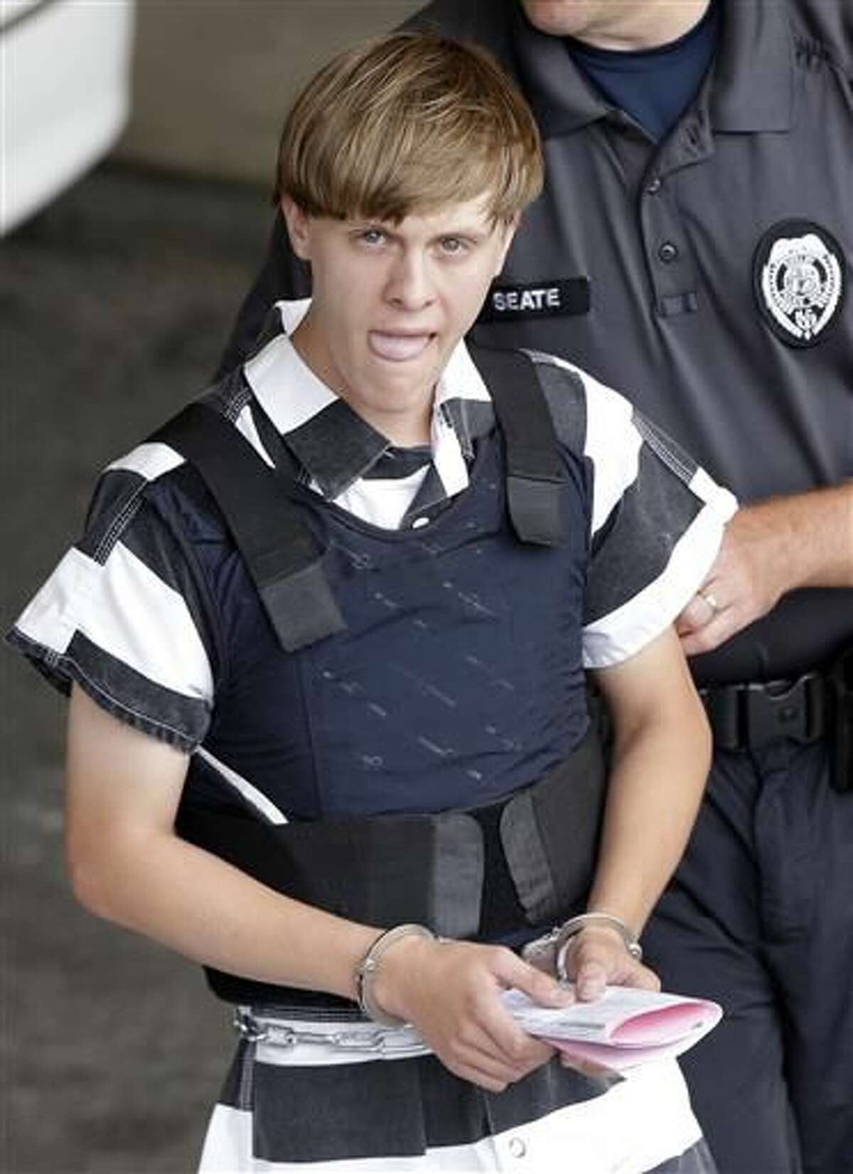 In this Thursday, June 18, 2015, file photo, Charleston, S.C., shooting suspect Dylann Storm Roof is escorted from the Cleveland County Courthouse in Shelby, N.C. After nine black parishioners were slain at a Charleston church, South Carolina did what many thought would never happen: It moved the Confederate flag off Statehouse grounds. (AP Photo/Chuck Burton)