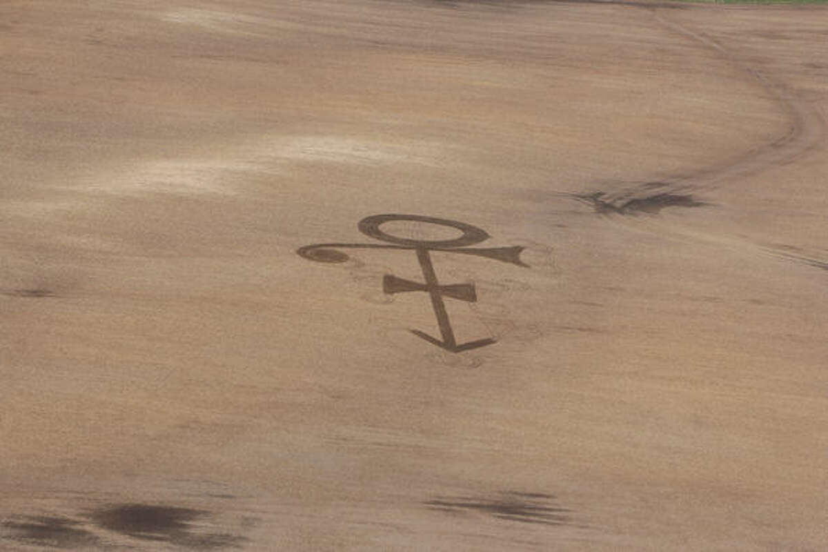 In this photo provided by Gene Hanson, a corn field shows the symbol of the late megastar Prince in Edgeley, N.D. The retired farmer Hanson, who always liked the song “Purple Rain,” plowed the football-size symbol Friday. He then got in his airplane and took a photo of the temporary tribute to Prince, who died April 21, at age 57, at his suburban Minneapolis compound. (Gene Hanson via AP)