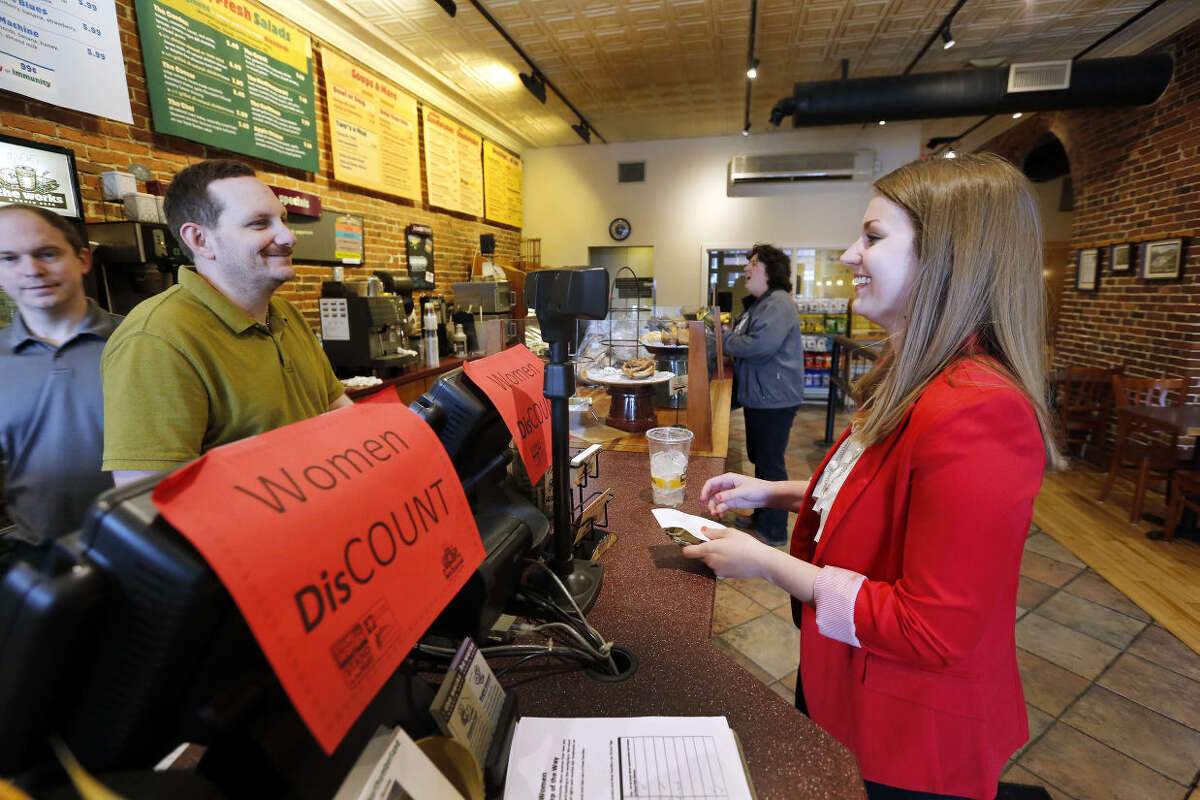 Molly Kepner, right, smiles after hearing the news of her discount from Tom Grover at The Works Bakery Cafe, Tuesday, April 12, 2016 in Concord, N.H. The New Hampshire bakery chain gave women a break in honor of Equal Pay Day charging them 79 percent of their bill. (AP Photo/Jim Cole)