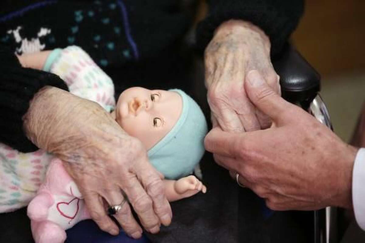 In a photo from April 14, 2016, Glen Hotchkiss, right, holds mother Phyllis Hotchkiss' hand as they talk at her nursing home in Adrian. Phyllis, 93, has dementia and is confined to a wheelchair and was involuntarily discharged from her nursing home this year to one further away from her family. (AP Photo/Carlos Osorio)