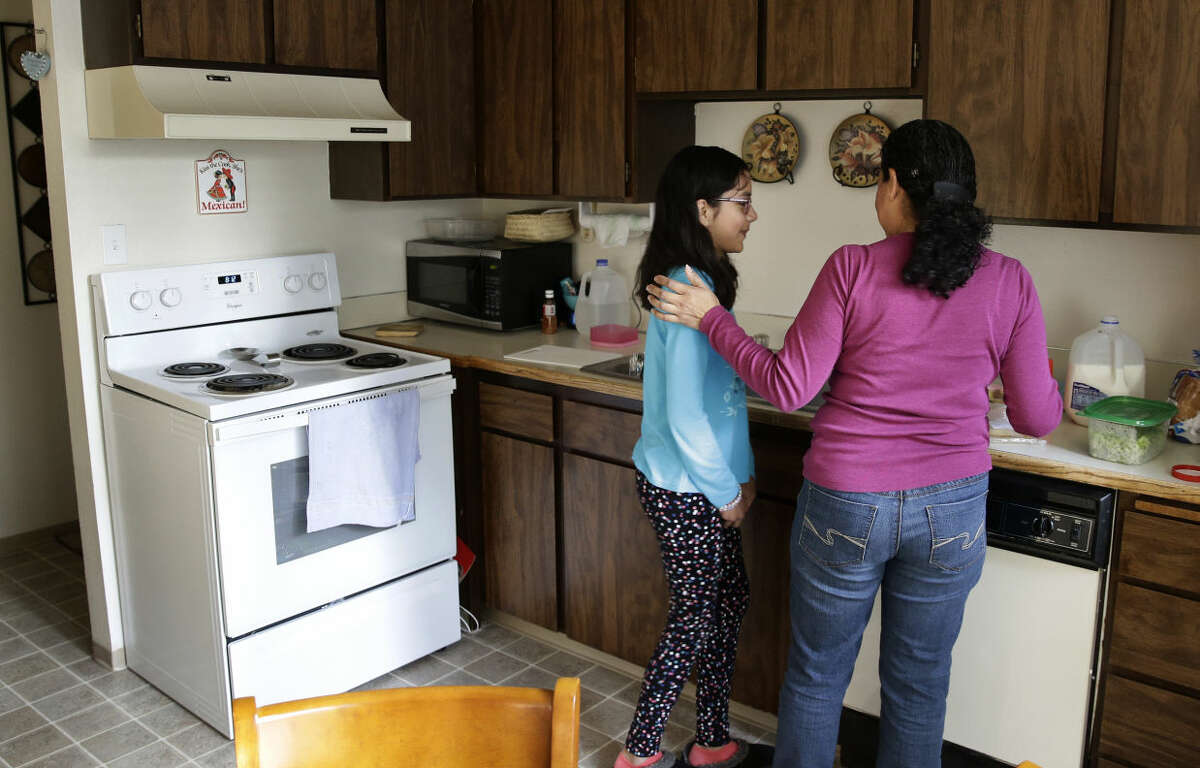 In this photo taken March 31, 2016, Teresa Garcia, right, helps her daughter, Alondra Miranda, 11, get ready for school at their home in Federal Way, Wash., south of Seattle. Garcia, who has spent 14 years in the United States illegally after staying beyond the expiration of her tourist visa in 2002, is one of millions who could be affected when the political fight over immigration comes to the U.S. Supreme Court on Monday, April 18, 2016 as the court weighs the fate of Obama administration programs that could shield roughly 4 million people from deportation and grant them the legal right to hold a job. (AP Photo/Ted S. Warren)