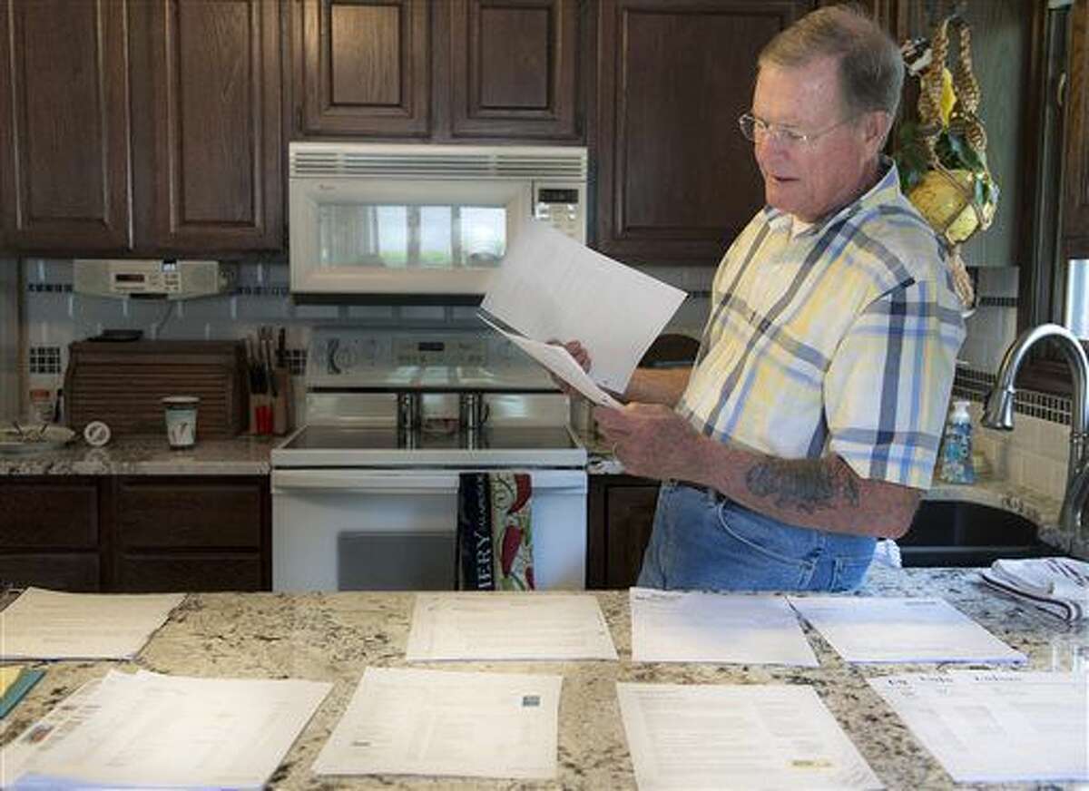 In this photo taken Monday, May 9, 2016, Chuck Zellers, of Lincoln, Neb., looks through some of the records and paperwork he has accumulated while trying to fix a Social Security error that declared him deceased. (Gwyneth Roberts/The Journal-Star via AP)