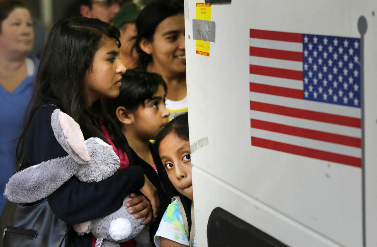 FILE - In this July 7, 2015 file photo, immigrants from El Salvador and Guatemala who entered the country illegally board a bus after they were released from a family detention center in San Antonio, Texas. The vast majority of immigrant children who arrive alone at the U.S. border are placed by the government with adults who are in the country illegally, federal data reviewed by The Associated Press show. (AP Photo/Eric Gay, File)