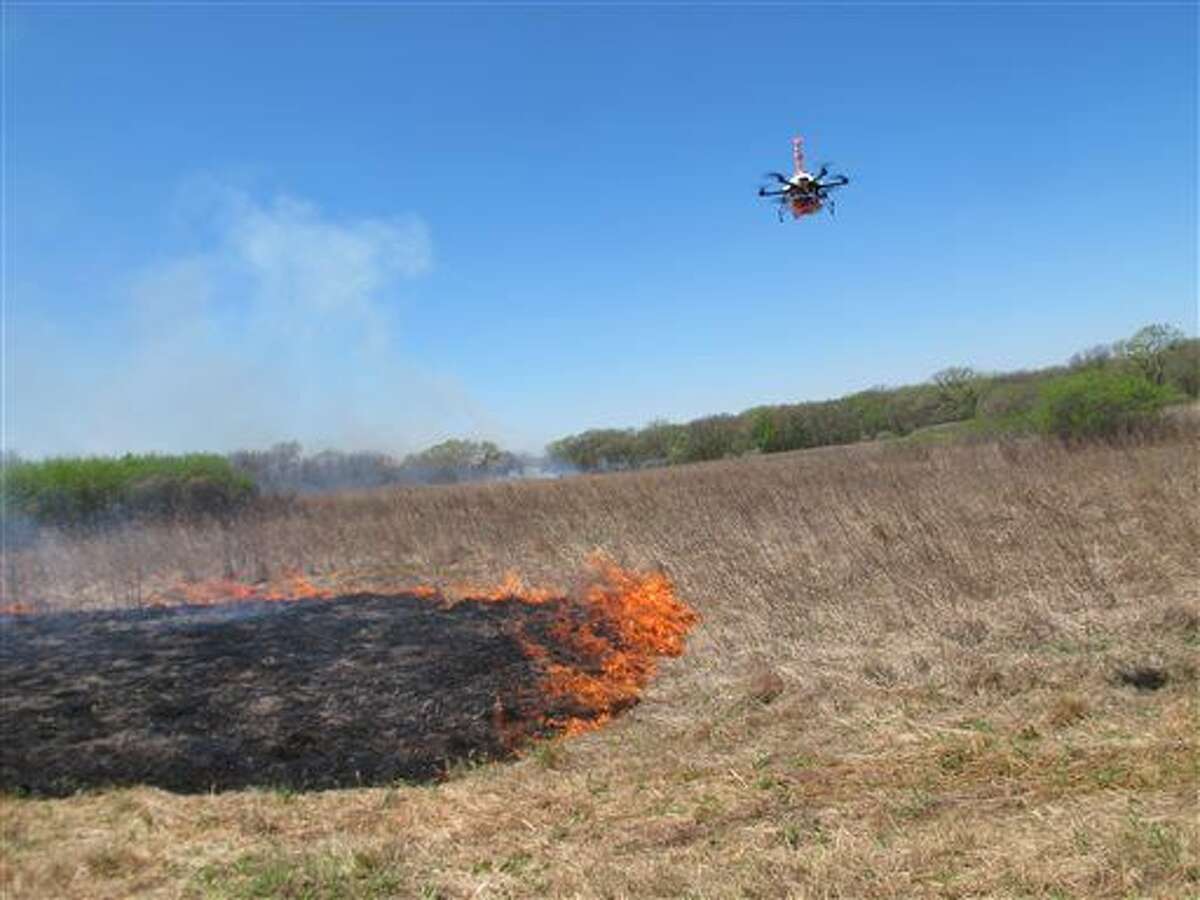 A drone designed to ignite controlled grass fires comes in for a landing in a field at the Homestead Monument of America in Beatrice, Neb., on Friday, April 22, 2016. University of Nebraska-Lincoln researchers are testing the drone as a possible tool for firefighters. (AP Photo/Grant Schulte)