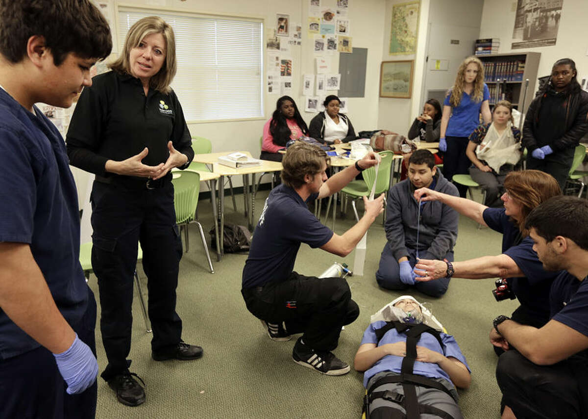In this photo taken on Tuesday, March 22, 2016, students examine patient Jacqueline Villalobo during an exercise in EMC First Responder class as emergency medical technician Gretchen Medel, second from left, speaks with Joshua Espinosa at Dozier-Libbey Medical High School in Antioch, Calif. In the latest incarnation of vocational education programs that once prepared young people not bound for college for skilled trades, the federal government and states like California are betting big that connecting high school studies to the increasingly technical knowledge required in fields such as manufacturing, agriculture and information technology will get more students to graduate, go on to complete at least some college and find well-paying jobs. (AP Photo/Ben Margot)