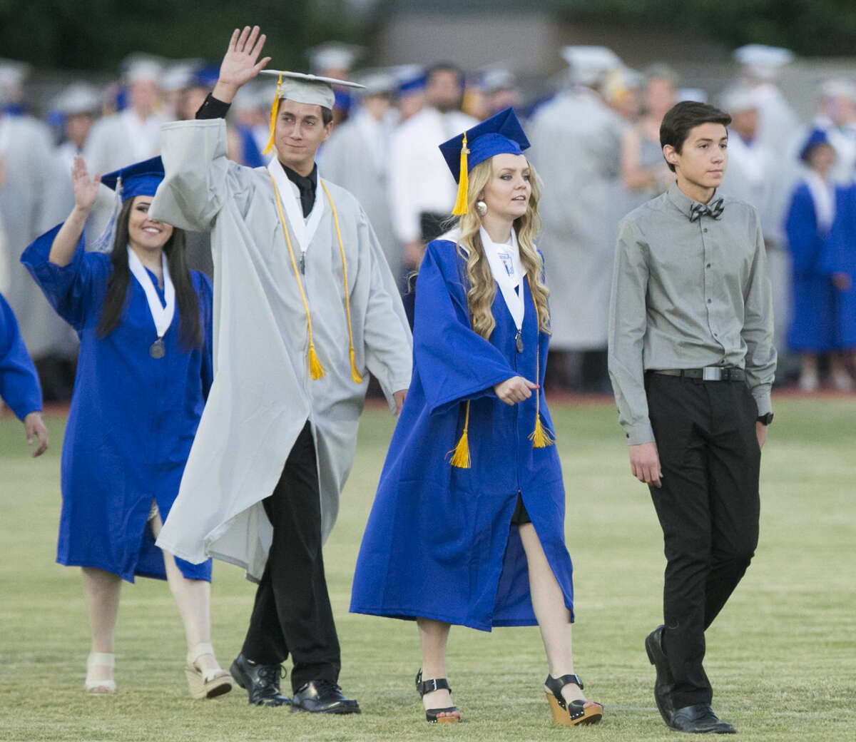 In this photo taken, Thursday evening, May 26, 2016, Stephen Dwyer, right, who could not wear a cap and gown nor sit with his classmates, leads graduates during the Dobson High School graduation in Mesa Ariz. Dwyer, who withdrew from classes his junior year to receive a lifesaving bone-marrow transplant to treat high-risk leukemia, returned for classes his senior year and he worked to catch. He is only 2.5 credits short of meeting the requirements to graduate from Dobson. He expects to graduate in December. The school and the Mesa Public Schools district officials said Dwyer may not wear his cap and gown, but can lead the Class of 2016 out at the beginning of the ceremony.(David Wallace/The Arizona Republic via AP) MARICOPA COUNTY OUT; MAGS OUT; NO SALES; MANDATORY CREDIT