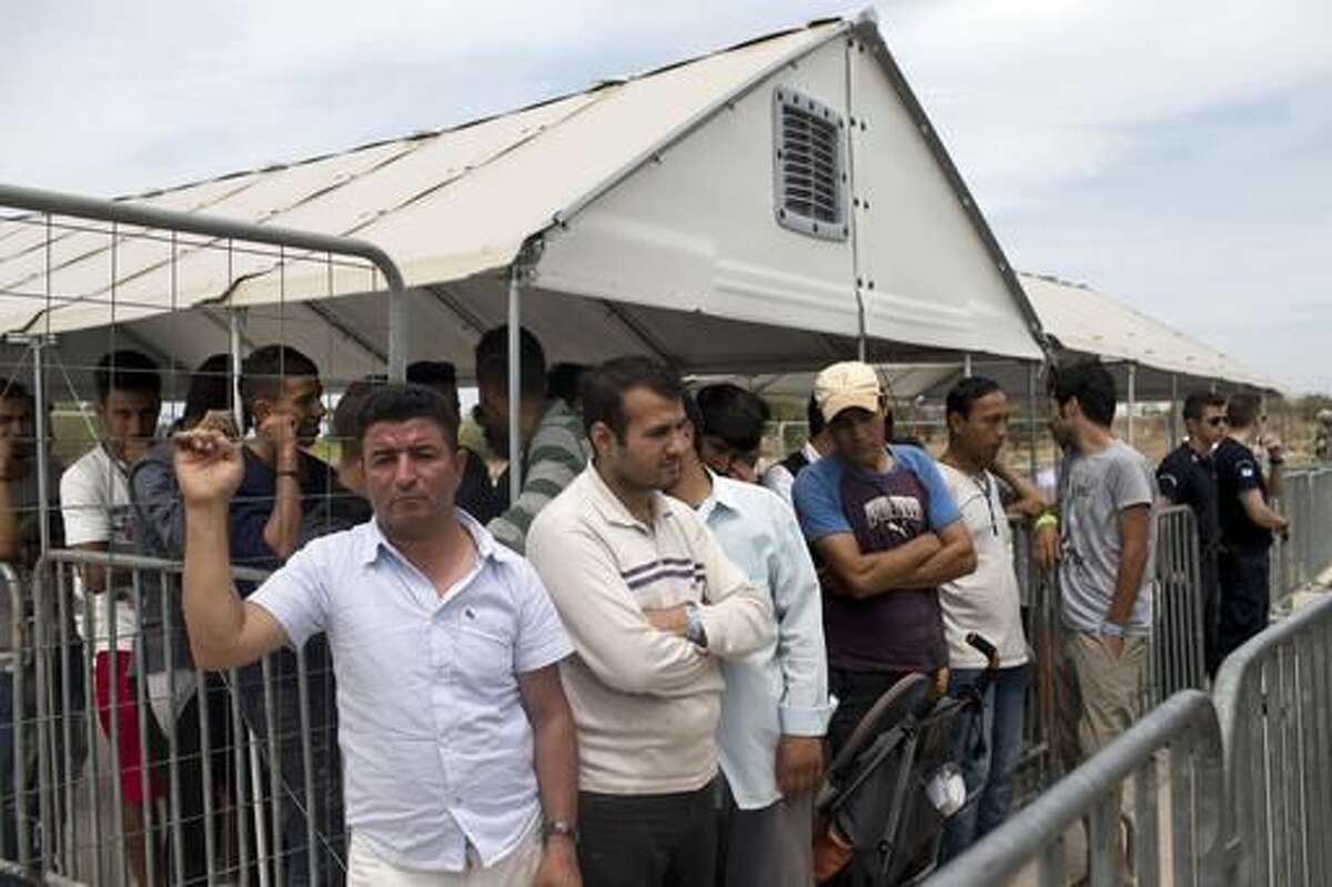 FILE - In this file photo taken on Monday, June 13, 2016, migrants who live in the Hellenikon refugee and migrant camp in Athens wait to register for asylum. A government official in Athens on Wednesday, Aug. 3, 2106 said to the Associated Press that there is no sign yet that a deal between the European Union and Turkey to stop migrants coming to Europe has faltered since the attempted military coup in the country. (AP Photo/Petros Giannakouris, File)
