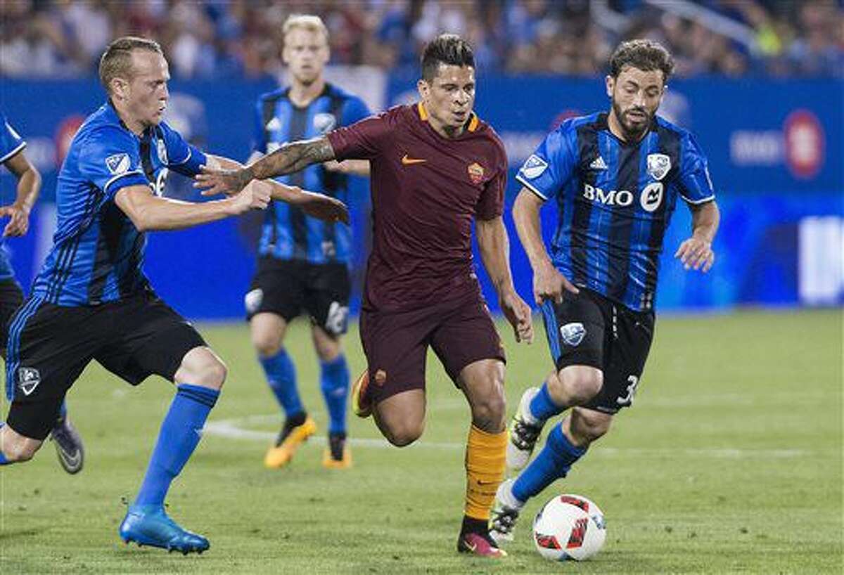 AS Roma's Juan Iturbe, center, holds off a challenge from Montreal Impact's Wandrille Lefevre, left, and Hernan Bernardello during the second half of a friendly soccer match in Montreal, Wednesday, Aug. 3, 2016. (Graham Hughes/The Canadian Press via AP)