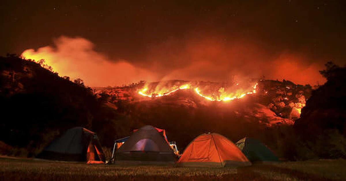 In this Tuesday, Aug. 2, 2016 photo, as campers bed down for the night along Putah Creek, the Cold fire burns slowly downhill on the Solano and Napa County line near Lake Berryessa, Calif. (Kent Porter/The Press Democrat via AP)