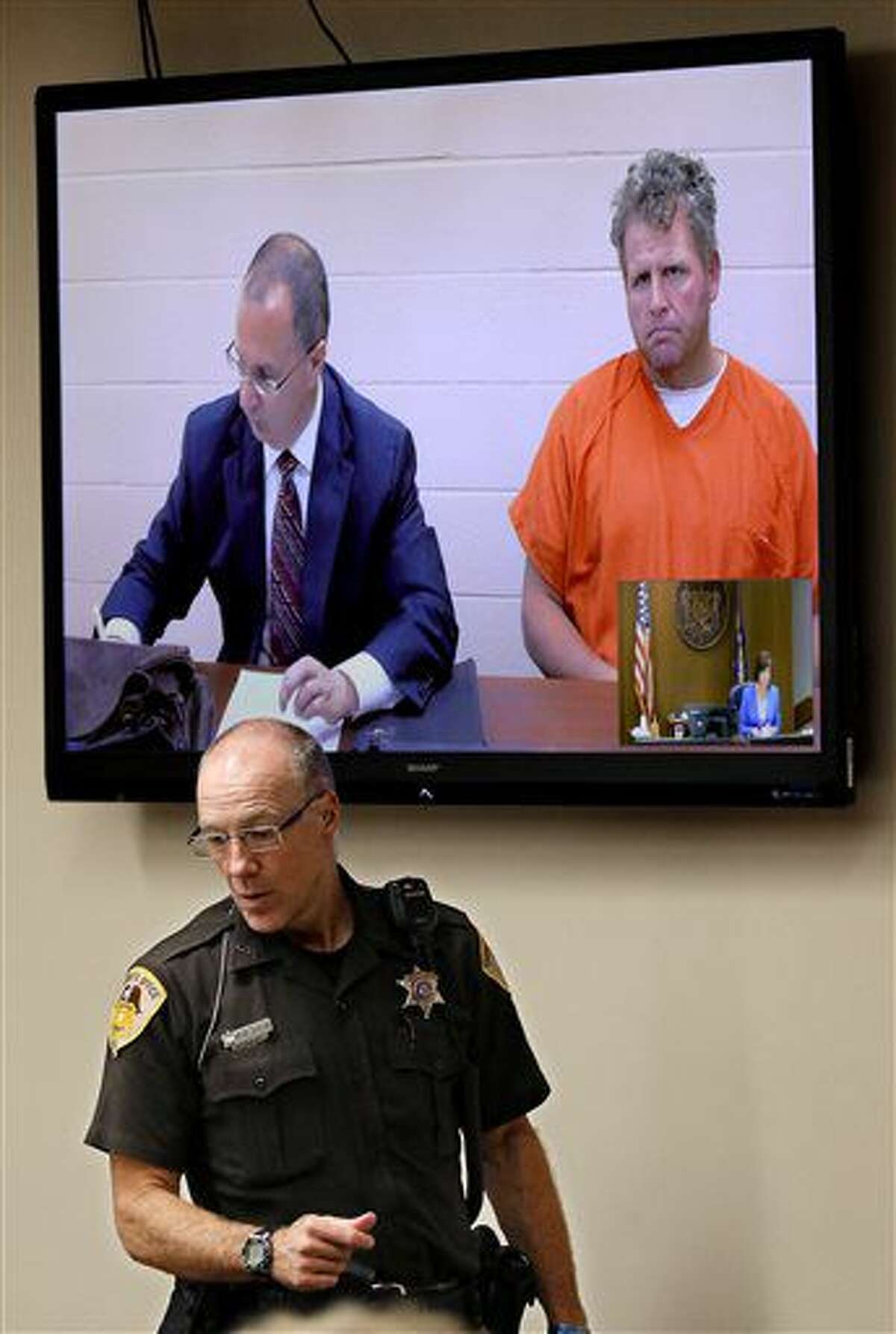 Sheriff's Deputy Scott Kuehn monitors the courtroom as Shane Helmbrecht appears via video to face formal charges Thursday, Aug. 4, 2016, in Eau Claire County Court in Eau Claire, Wis. Helmbrecht who was charged with fatally shooting his neighbor, told police he was constantly hearing voices in his head. (Dan Reiland/The Eau Claire Leader-Telegram via AP) MANDATORY CREDIT