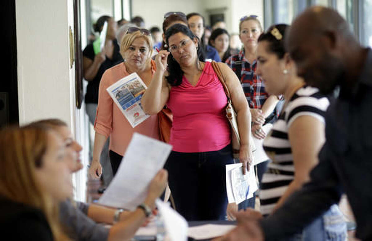 In this Tuesday, July 19, 2016, photo, Reina Borges, left, stands in line to apply for a job with Aldi at a job fair in Miami Lakes, Fla. On Friday, Aug. 5, the Labor Department issues its jobs report for July. (AP Photo/Lynne Sladky)