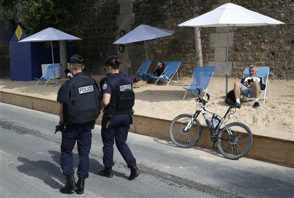 French police officers patrol at Paris Plage (Paris Beach) Friday, Aug. 5, 2016 in Paris. Paris Plage is an artificial beach set up on the right bank of the Seine river with palm trees, outdoor showers and hammocks. Numerous summer festivals have been canceled because maximal security cannot be assured despite additional injection of security forces. (AP Photo/Michel Euler)