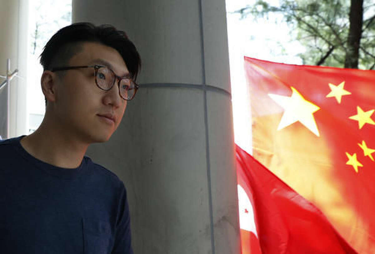 Hong Kong localist leader Edward Leung Tin-kei walks past a Chinese national flag outside a court after he was charged with rioting in Hong Kong, Friday, Aug. 5, 2016. Amid a dispute over candidates excluded on political grounds, Hong Kong's government on Friday posted the names of those approved to run in the territory's most contentious Legislative Council elections since reverting to Chinese rule almost two decades ago. The placard reads "Punish rioters severely, pay back in prison".(AP Photo/Kin Cheung)