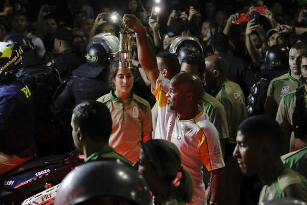 David Vieira Bisbo, a bar owner in the Chapeu Mangueria slum, holds the Olympic flame after his Olympic torch run along the streets of Copacabana, as the torch makes its way to the opening ceremony of the 2016 Summer Olympics in Rio de Janeiro, Brazil, early Friday, Aug. 5, 2016. (AP Photo/Gregory Bull)